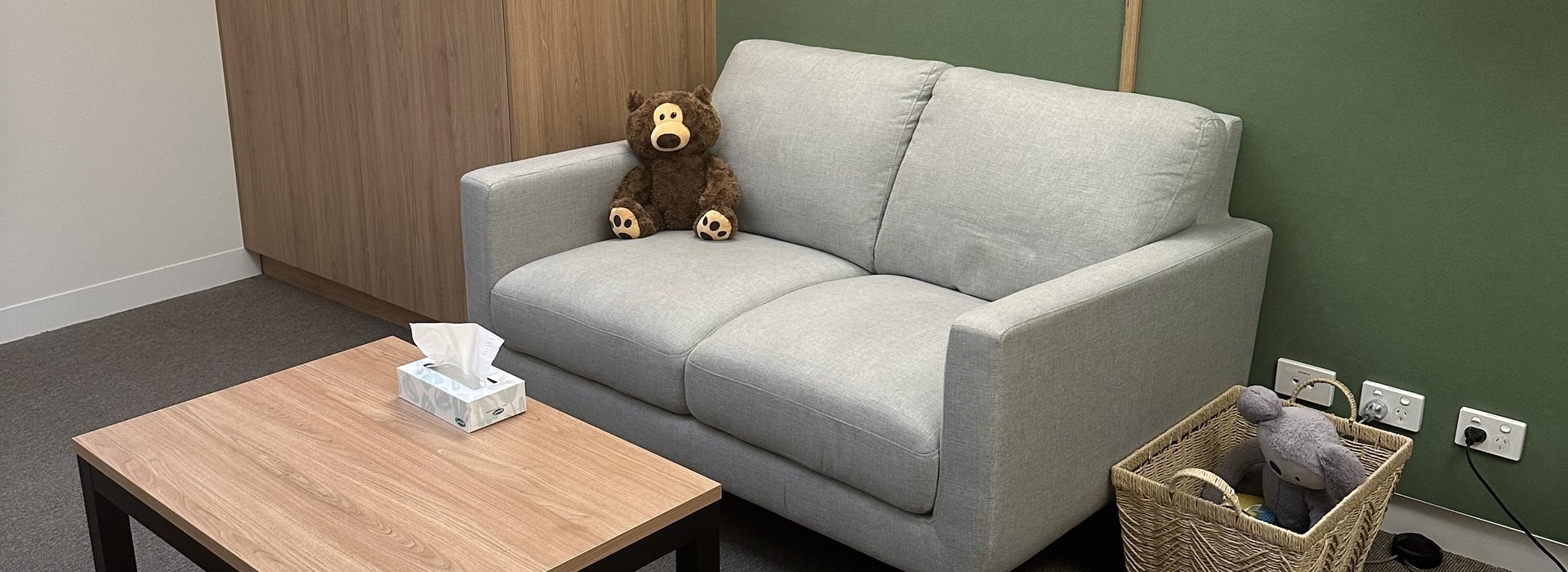 A couch with a teddy bear on it in a warmly lit room
