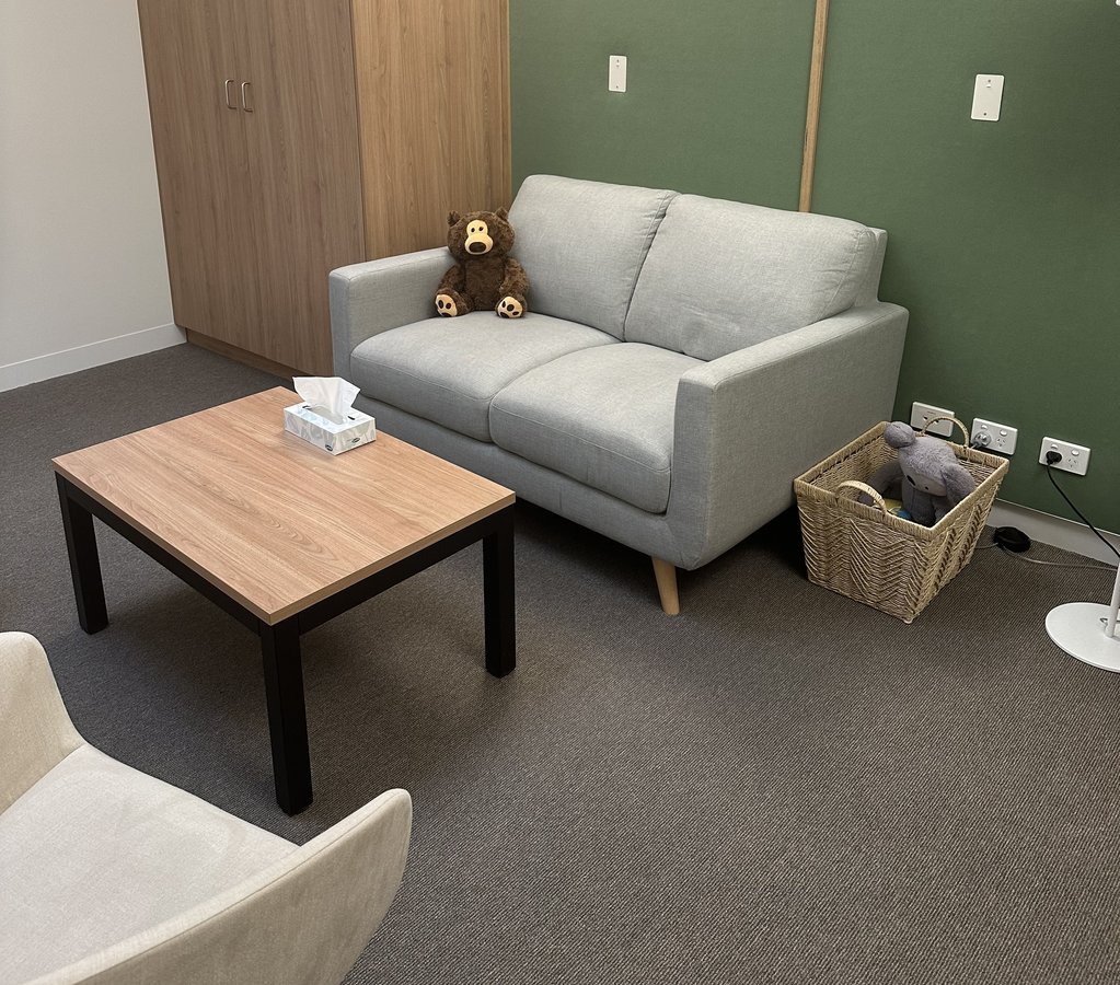 A couch with a teddy bear on it in a warmly lit room