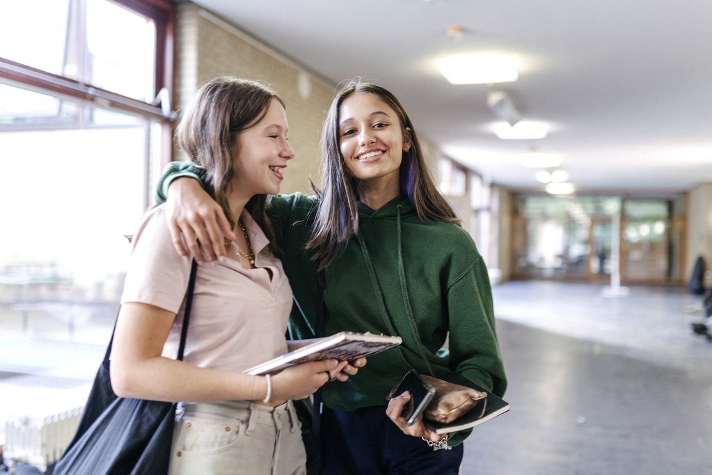 Two teenage girls standing in a school hallway