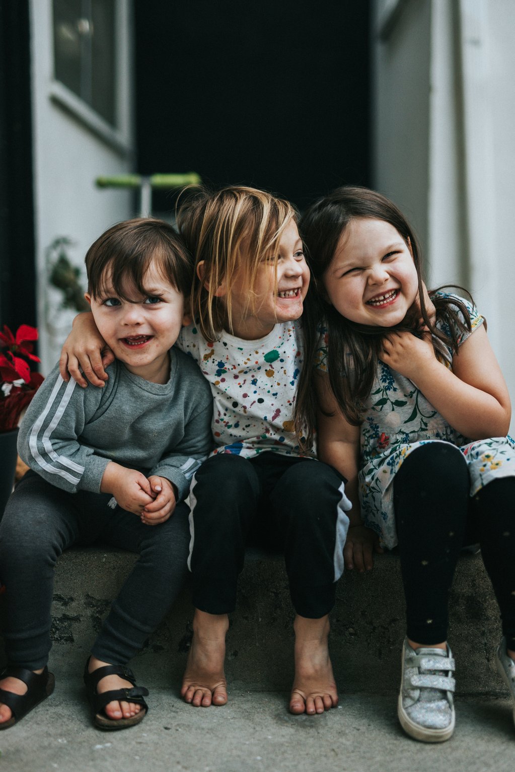 three smiling children sitting on a step