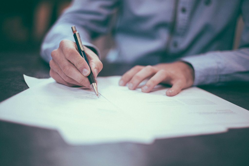 person writing on paper with a pen